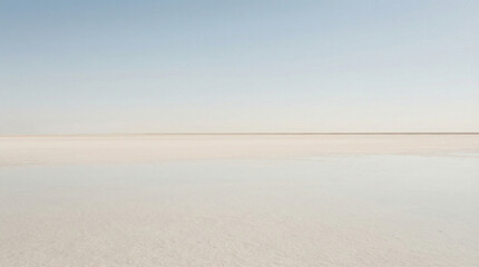 Obraz premium A captivating vista unfolds, where a salt flat extends limitlessly under a pastel blue sky. The horizon appears as a gentle, hazy line, creating a dreamy and ethereal atmosphere.