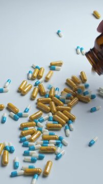 Hand pours mixed capsules from amber bottle onto table, showing overdose risk and confusion of supplements with medicine.
