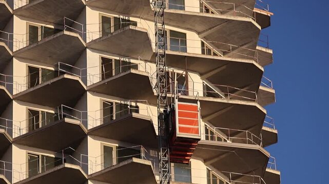 A freight construction elevator lifts cargo to a height during the construction of a high-rise building. Lifting loads to a height during construction. Construction technologies.