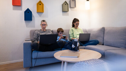 Family on couch using digital devices at home