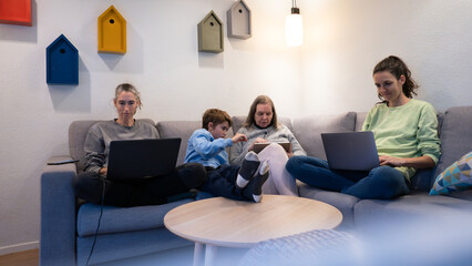 Family generations connecting with digital devices on sofa