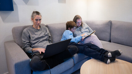 Family members relaxing on sofa using technology at home