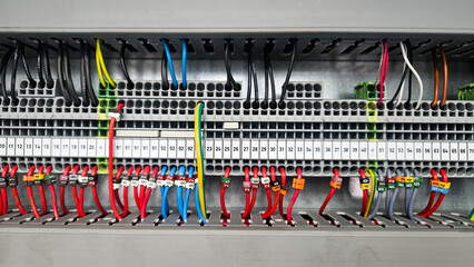 Intricate wiring and terminal blocks within an industrial electrical control panel, showcasing organized cable management and electrical connections.