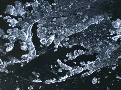 Aerial view of shattered ice floes create a mesmerizing dance of light and shadow on the dark waters, Vistula river, Nowe Gniewniewice, Masovian Voivodeship, Poland.