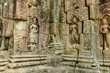 Intricate sandstone carvings of devata figures adorn the weathered wall of Ta Som temple in Cambodia's Angkor region. The detailed bas-reliefs and ornate patterns are highlighted by natural light