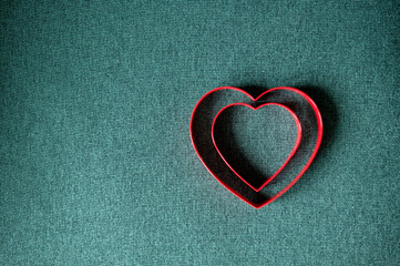 top view of two red hearts on green background with copy space.