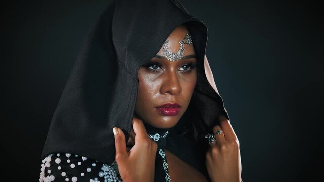 Portrait fantasy gothic african american woman vampire in night dark room. Mystical face creative halloween costume medieval queen. Black dress hood on head. Sexy girl evil queen. larp concept fairy