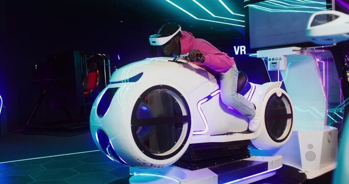 Man wearing virtual reality glasses play online video game with motorbike simulator