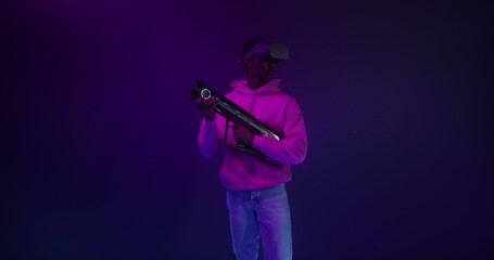 A man in a virtual reality headset with a blaster in his hands in a VR studio