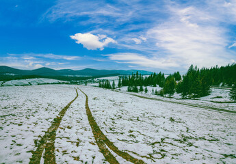 Traces of the car on a snow-covered field. Mountain landscape in winter