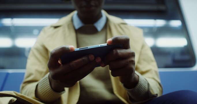 A man in headphones plays a mobile phone in the subway