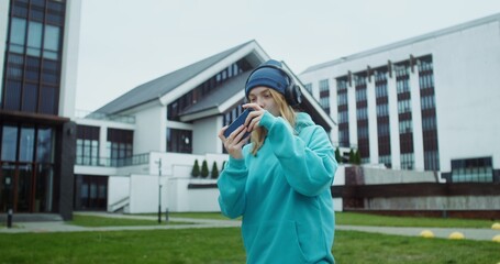 Fototapeta premium Woman playing online game on mobile phone while walking on the street