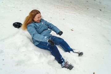 Adult woman laughing after slipping on snow during winter walk