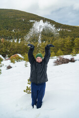 Happy man tossing snow in a winter forest