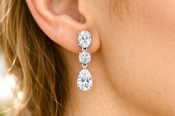 A woman wearing a pair of earrings with three large diamonds