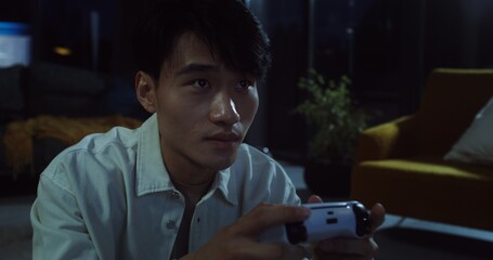 Young man playing video games at home in the evening