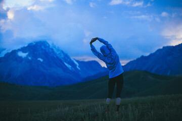 Woman runner stretching  at  the beautiful grassland mountain top
