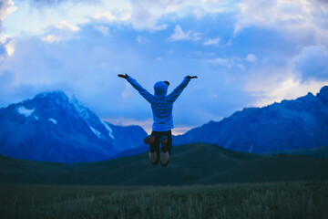 Woman runner jumping at  the beautiful grassland mountain top