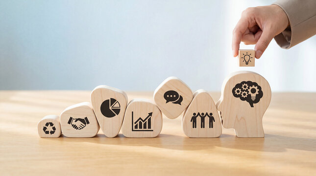 Hand arranging wooden puzzle pieces with business icons representing teamwork and problem solving concepts