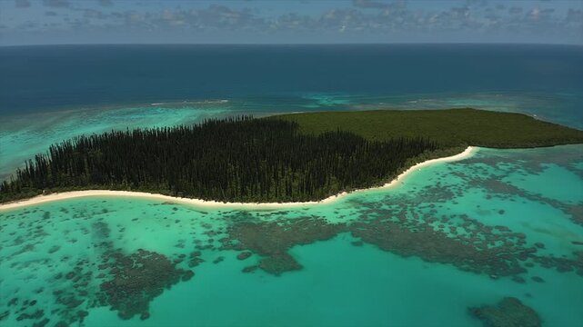 Deserted Ilot Brosse, or Brush Island, in Isle of Pines, half covered in forest of iconic columnar pine trees from the air, slow counterclockwise rotation.