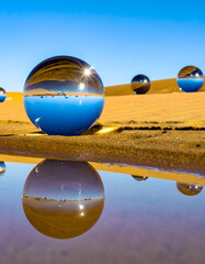 Chrome Metallic Spheres on Golden Sand Dunes Under Blue Sky

