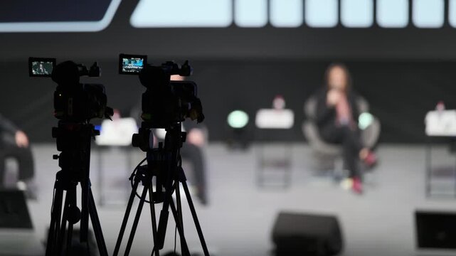 Cinematic scene of live talk show with blurred host on stage while cameras capture proceedings and crew monitor feeds