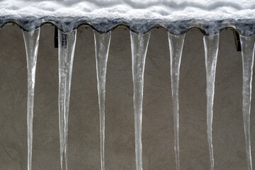 Icicles hanging from an edge create a winter scene showing cold weather and ice formation during winter months in a snowy environment