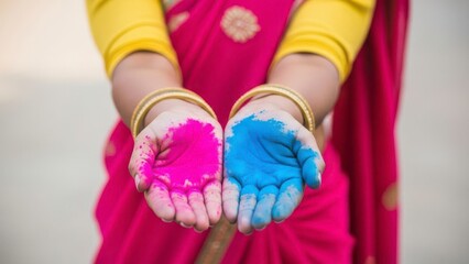 A woman in a vibrant pink sari holds colorful powders in her hands, symbolizing the Holi festival holi festival