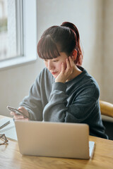 Young Woman Using Smartphone at Desk During Remote Work
