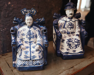 Chinese porcelain figurines of imperial couple in blue and white glaze at flea market. Vintage items.