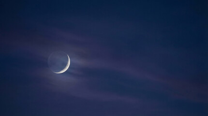 Crescent moon in dark sky with clouds at twilight for Ramadan  