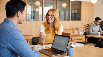 Young professionals collaborating and discussing work in modern office setting with laptops and coffee