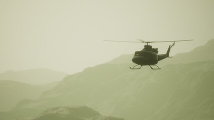 A helicopter hovers gracefully in the hazy air above rugged mountains. The early morning light casts a soft glow, creating a serene atmosphere in the wilderness. © icetray