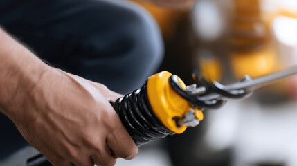 Mechanic hand inspects shock absorber, showcasing intricate details of component. focus on yellow and black parts highlights precision involved in automotive maintenance