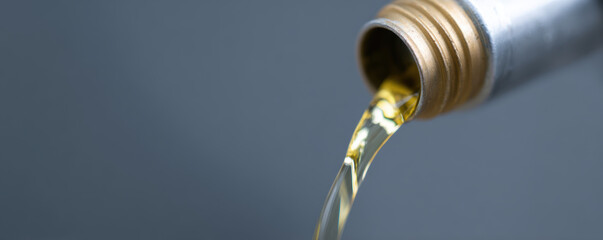 Golden oil pours from oil filler cap, showcasing close up view of liquid smooth texture and vibrant color. image captures essence of automotive maintenance and care