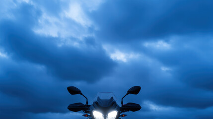 Low angle photography shot captures motorcycle against dramatic sky filled with dark clouds, evoking sense of adventure and mystery. motorcycle headlights shine brightly, adding to striking visual