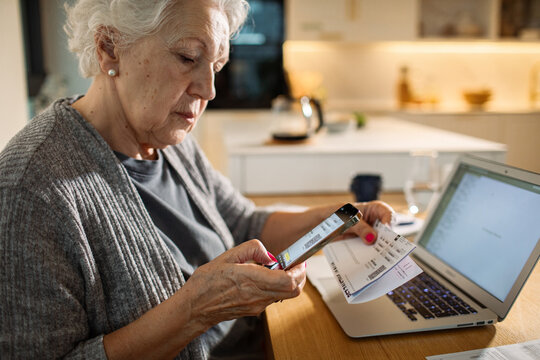 Senior woman paying bills online at home