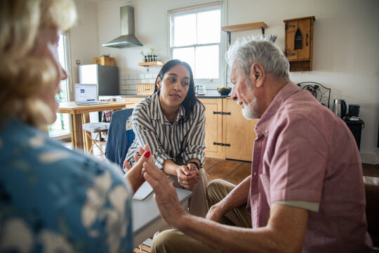 Social worker consulting with senior couple in home kitchen