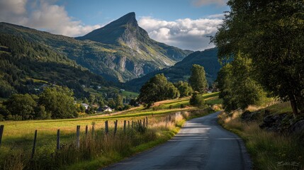 A winding road leads through a verdant valley towards a majestic, sharply peaked mountain under a partly sunny sky
