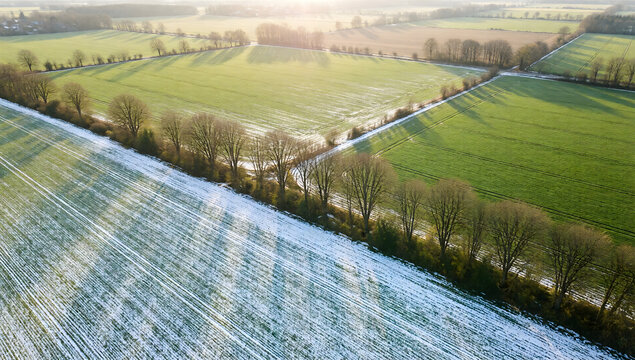 Aerial view of countryside waking up after winter patchy snow and green fields