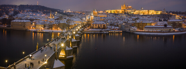 Naklejka premium High Resolution Panorama Picture of Winter Snowy Prague Old Town with Prague Castle and Charles Bridge above River Vltava during Sunset , Czech republic
