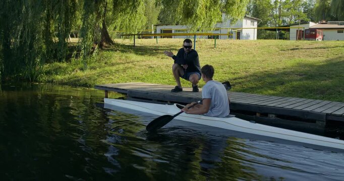 A coach gives a rower some advice and he sets off from the pier.