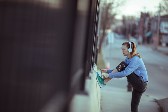 Woman runner tying shoe on city sidewalk