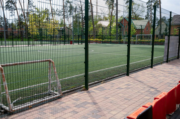 soccer field behind the fence, football field with goals and white lines on the grass © Anna