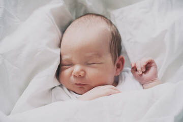 Newborn sleep at first days of life. Portrait of new born baby one week old in crib in cloth background.