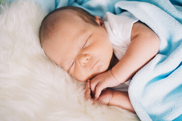 Newborn sleep at first days of life. Portrait of new born baby one week old in crib in cloth background.