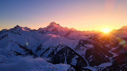 Snow covered mountains at sunset with vibrant colors and clear sky