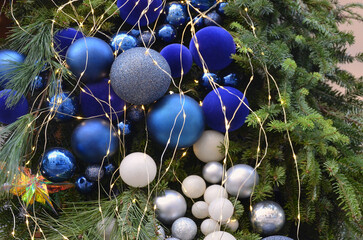 Blue and white shadows balls christmas tree decorations and small yellow lights hanging on pine tree branches.Winter holiday decorations,greeting  concept.