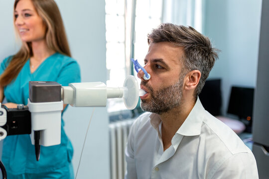 Medical Professional Conducting Spirometry Test for male Patient. Respiratory Therapist Monitoring Lung Function Results. Healthcare Specialist Performing Pulmonary Assessment in Hospital.