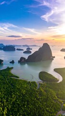 Aerial view of a serene bay at sunrise, islands dotting the calm water, framed by lush green foliage